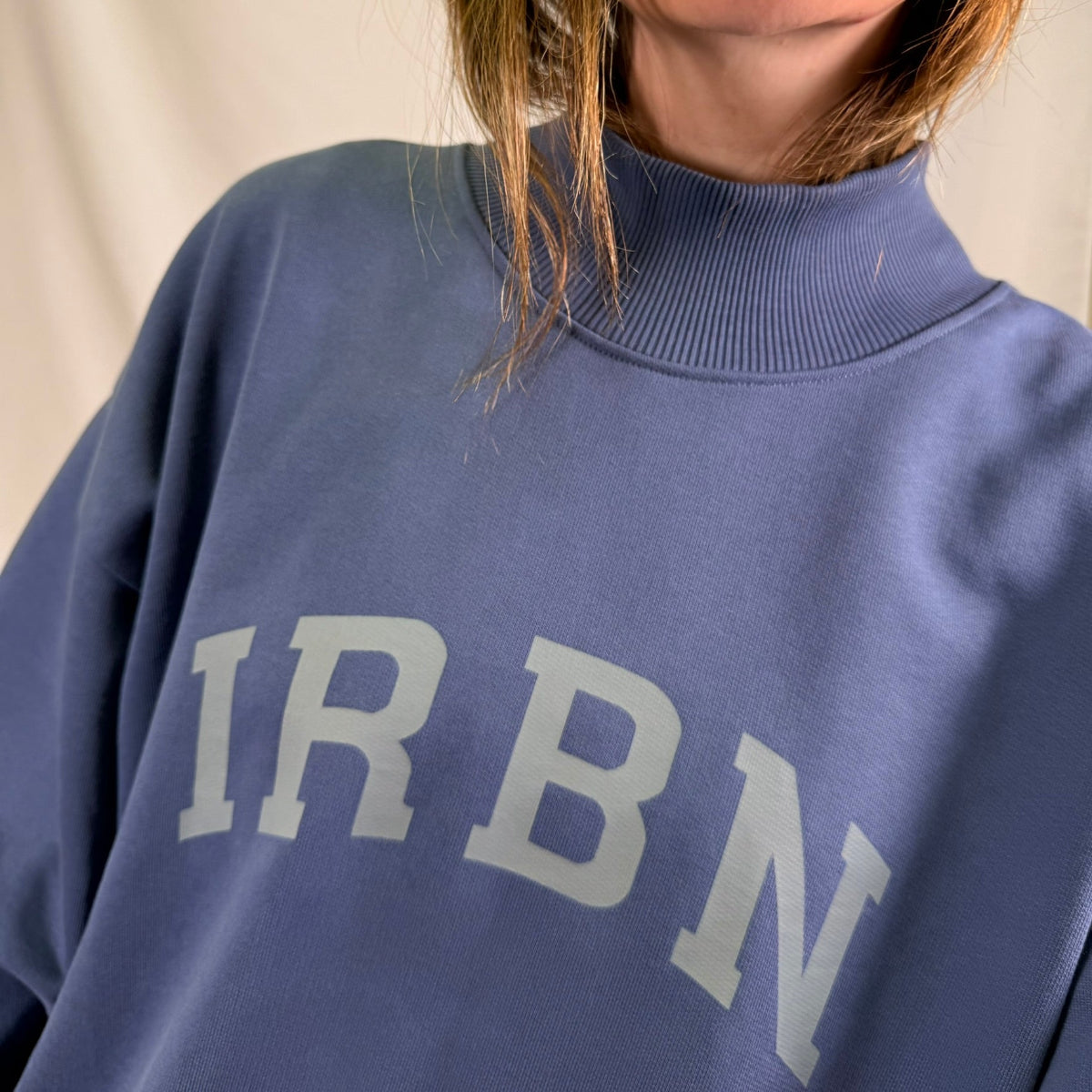 Close-up of IRBN arched chest print and mock neck collar on Blue Indigo sweatshirt, tonal print on 400gsm organic cotton