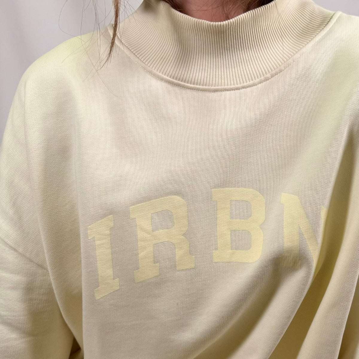 Close-up of IRBN arched chest print on Cannoli Cream sweatshirt, tonal print on 400gsm organic cotton