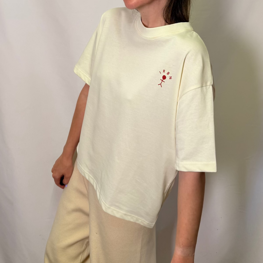 IRBN boxy t-shirt in Cannoli Cream, three-quarter front view showing embroidered stick figure logo and boxy fit, 250gsm organic cotton