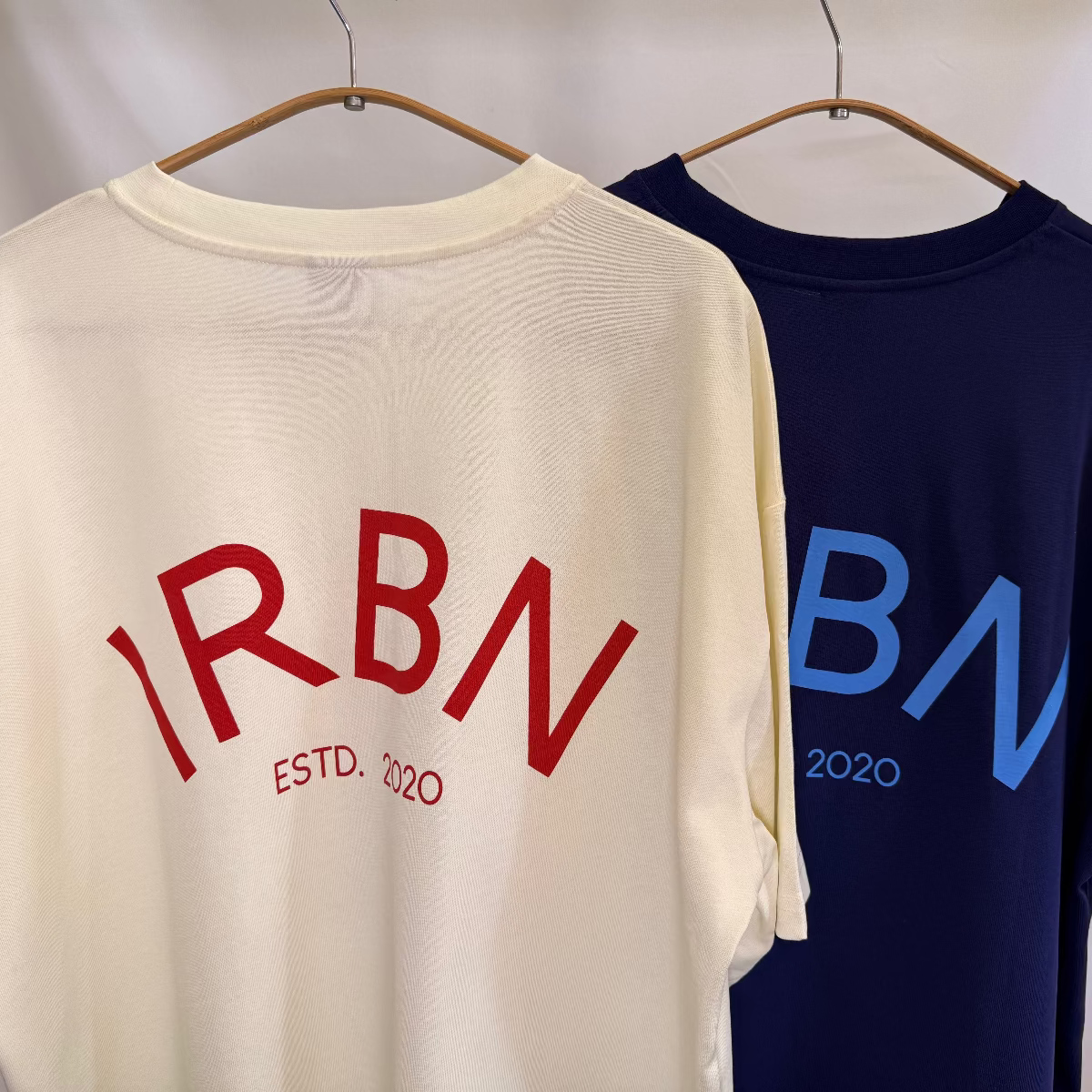 IRBN boxy t-shirt in both launch colourways, Cannoli Cream with red print and Navy with blue print, 250gsm GOTS-certified organic cotton