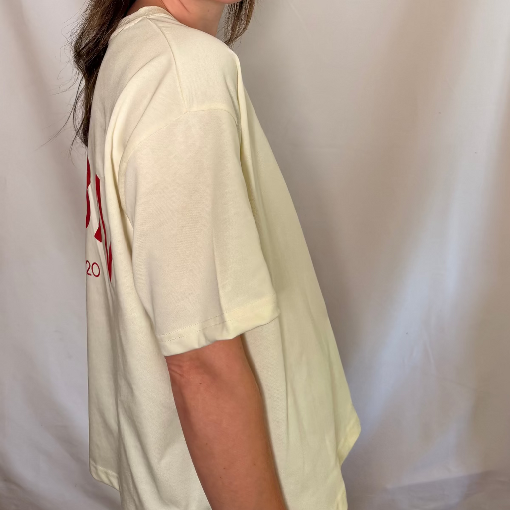 IRBN boxy t-shirt in Cannoli Cream, side-back view showing IRBN ESTD. 2020 print and dropped shoulder silhouette, 250gsm organic cotton