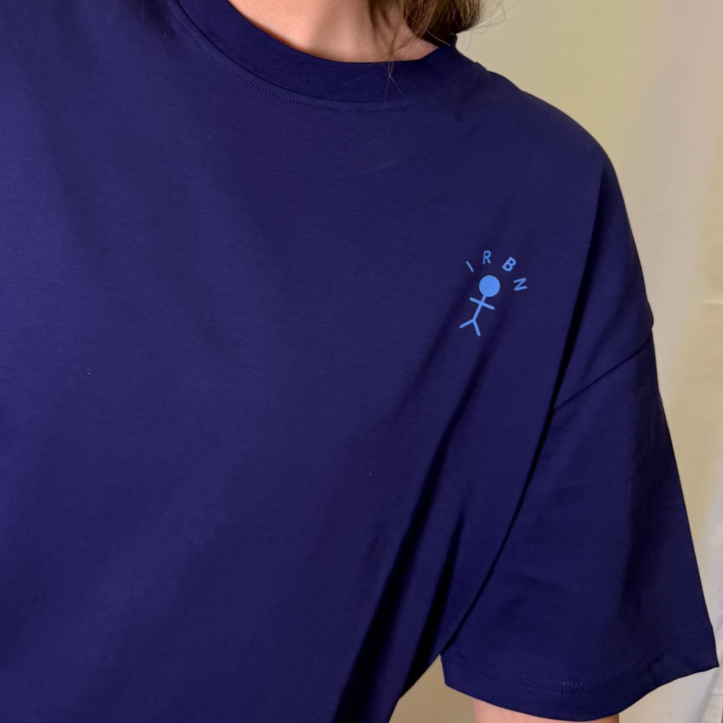 Close-up of embroidered IRBN stick figure logo on Navy boxy t-shirt, 250gsm GOTS-certified organic cotton made in Portugal